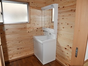 手洗い場の壁は木目のデザインとなっています。鏡も扉式になっておりすっきりと収納することができます。小窓もあり明るい空間となっています。